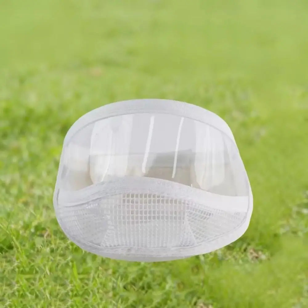 Bozal transparente blanco para gatos con malla de ventilación sobre césped.